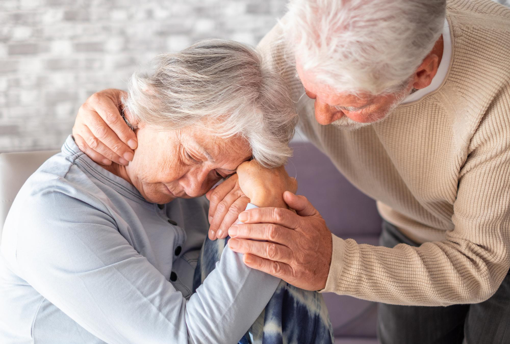 Un hombre mayor consolando a una mujer mayor que está angustiada, mostrando el impacto emocional del Alzheimer y la importancia de explorar tratamientos naturales.